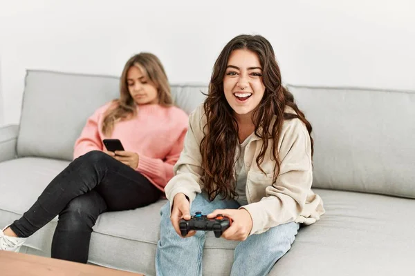 女の子再生ビデオゲームと彼女のガールフレンド退屈な使用スマートフォンにホーム — ストック写真
