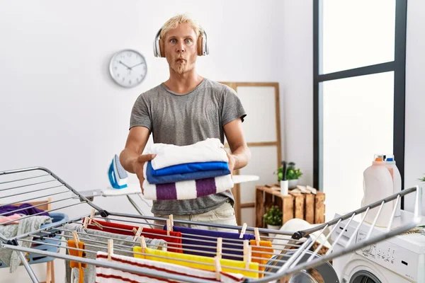 Young Blond Man Listening Music Doing Laundry Making Fish Face — Stockfoto