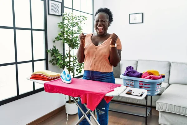 Young African Woman Ironing Clothes Home Excited Success Arms Raised — Photo