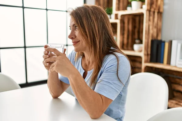 Biała Kobieta Średnim Wieku Pije Szklankę Wody Siedzącej Stole Domu — Zdjęcie stockowe