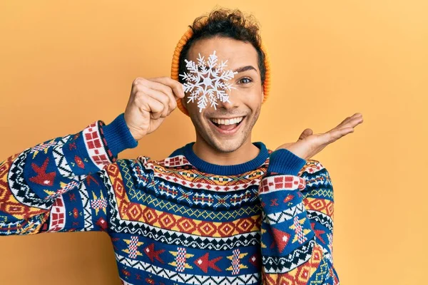 Young Handsome Man Holding Snowflake Wearing Winter Sweater Celebrating Achievement — Stockfoto