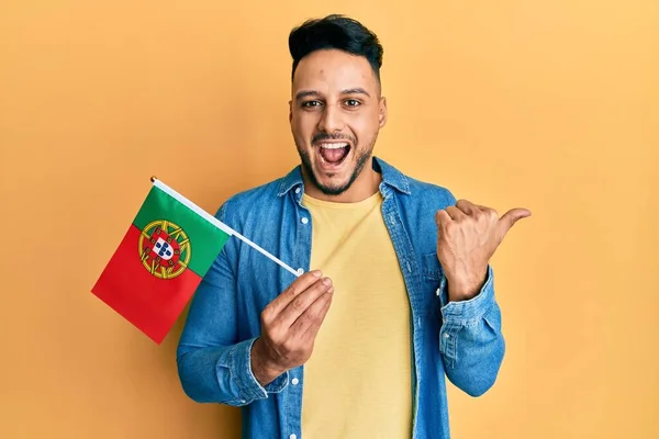 Young Arab Man Holding Portugal Flag Pointing Thumb Side Smiling —  Fotos de Stock