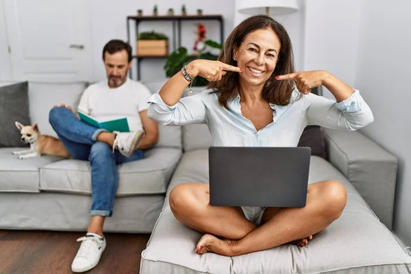 Hispanic Middle Age Couple Home Woman Using Laptop Smiling Cheerful — Stockfoto