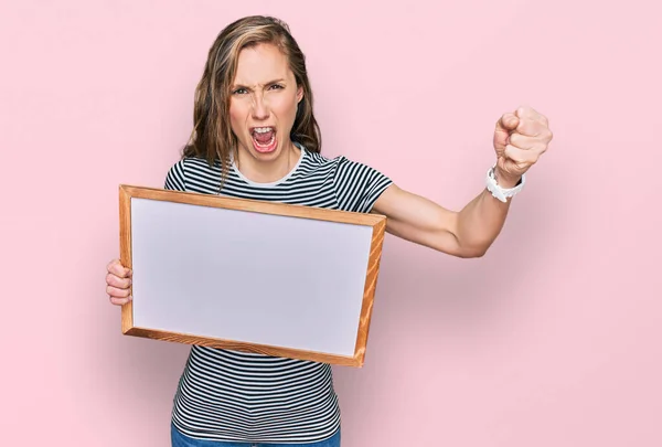 Young Blonde Woman Holding Empty White Board Annoyed Frustrated Shouting — Foto de Stock