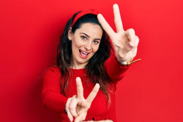 Молода Іспаномовна Жінка Повсякденному Одязі Посміхається Язиком Показуючи Пальці Обох — стокове фото