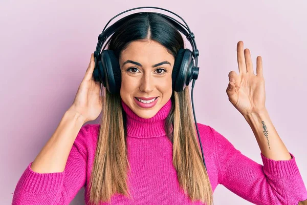 Young Hispanic Woman Listening Music Using Headphones Doing Sign Fingers — Foto de Stock