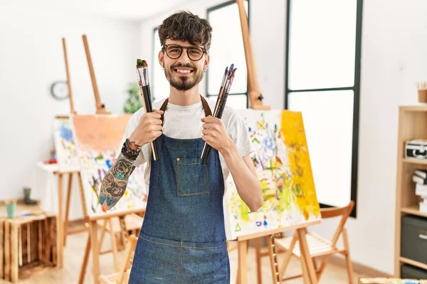 Joven Artista Hispano Sonriendo Feliz Sosteniendo Pinceles Estudio Arte — Foto de Stock