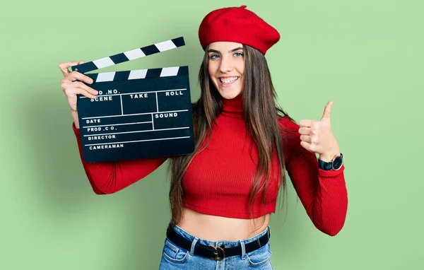 Young Brunette Teenager Holding Video Film Clapboard Smiling Happy Positive — Zdjęcie stockowe