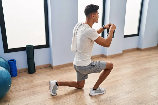 Genç İspanyol adam gülümsüyor spor merkezinde kettlebell kullanıyor.