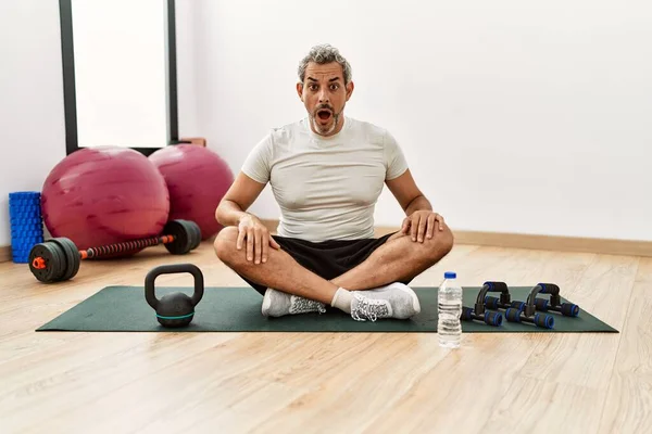 Middle Age Hispanic Man Sitting Training Mat Gym Scared Amazed — Zdjęcie stockowe
