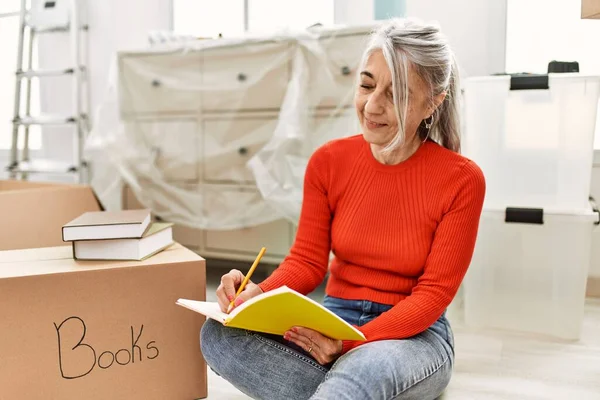 中年白髪の女性笑顔自信に満ちた書き込み上の本に新しい家 — ストック写真