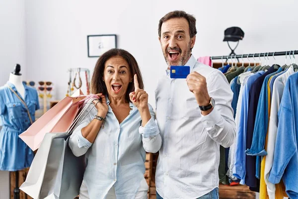 Hispanic Middle Age Couple Holding Shopping Bags Credit Card Pointing — Stock fotografie