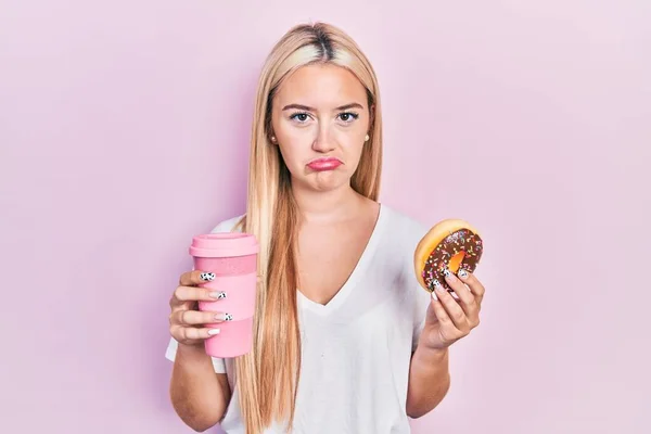 Young Blonde Girl Eating Doughnut Drinking Coffee Depressed Worry Distress — Fotografia de Stock