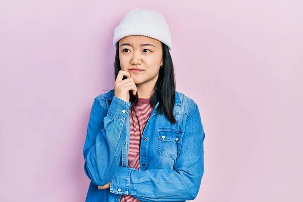 Young Chinese Girl Wearing Cute Wool Cap Serious Face Thinking — стоковое фото
