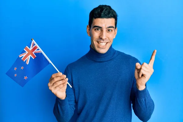 Hombre Hispano Guapo Sosteniendo Nueva Bandera Zelanda Sonriendo Feliz Señalando —  Fotos de Stock