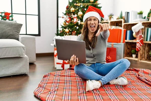 Young Latin Woman Using Laptop Sitting Christmas Tree Pointing Displeased — стоковое фото