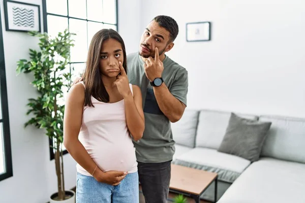 若い異人種間のカップルは 赤ちゃんを期待し あなたのジェスチャーを見て目を指して妊娠中の腹に触れる 疑わしい表現 — ストック写真