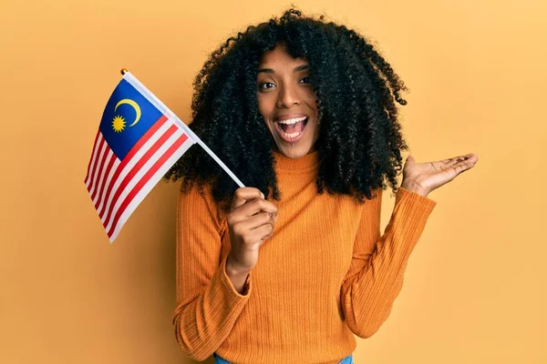 African American Woman Afro Hair Holding Malaysia Flag Celebrating Achievement — стоковое фото