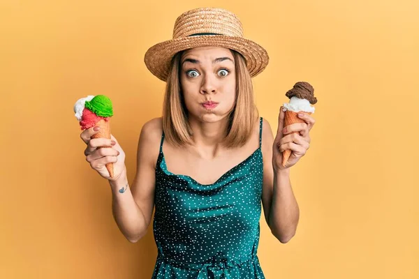 若い白人ブロンドの女性は面白い顔でアイスクリームコーンパフ頬を食べています 空気を吸い込み空気を吸い込み — ストック写真