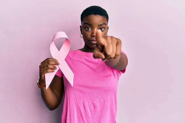 Young African American Woman Holding Pink Cancer Ribbon Pointing Finger — Foto de Stock