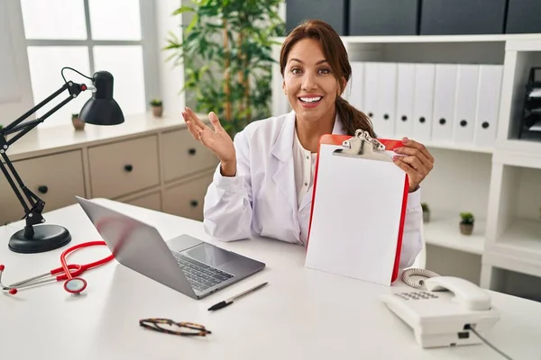 Hispanic Doctor Woman Holding Clipboard Celebrating Achievement Happy Smile Winner — Stock fotografie