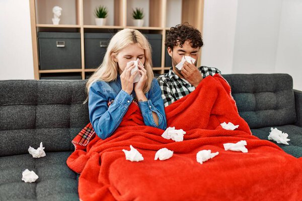 Young ill couple using napkin sititng on the sofa at home.