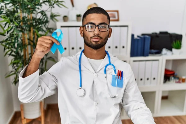 Young Indian Doctor Holding Blue Ribbon Thinking Attitude Sober Expression — Stok fotoğraf