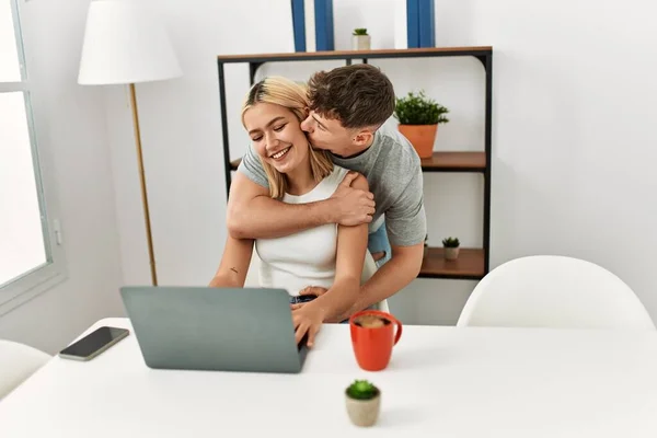 Genç Beyaz Bir Çift Evdeki Masada Dizüstü Bilgisayarla Sarılıp Öpüşüyor — Stok fotoğraf
