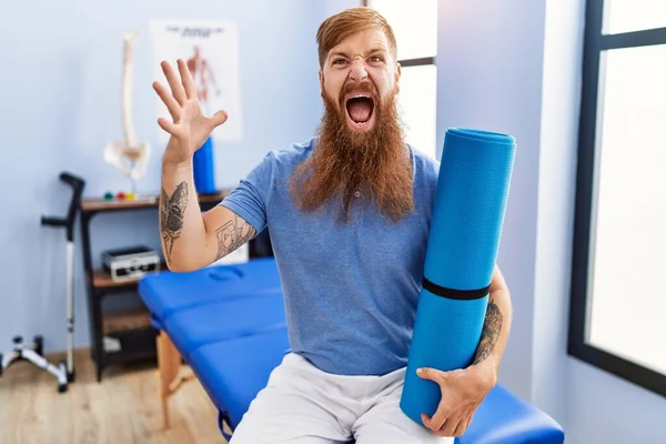 Redhead Man Long Beard Holding Yoga Mat Rehabilitation Clinic Celebrating — Zdjęcie stockowe