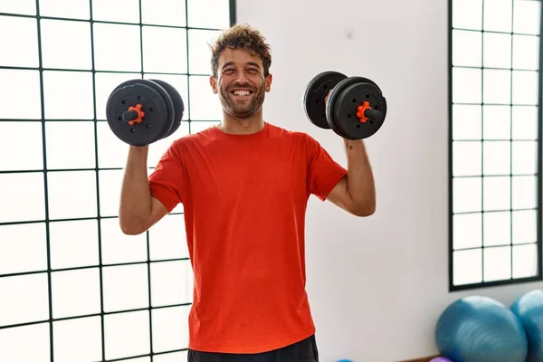 Giovane Uomo Ispanico Sorridente Allenamento Fiducioso Utilizzando Manubri Centro Sportivo — Foto Stock