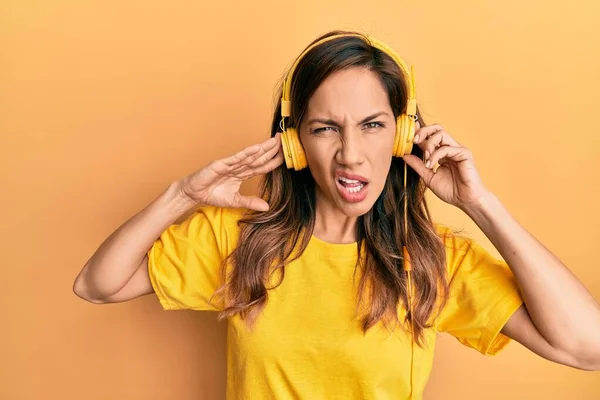 Young Latin Woman Listening Music Using Headphones Shock Face Looking — Stockfoto