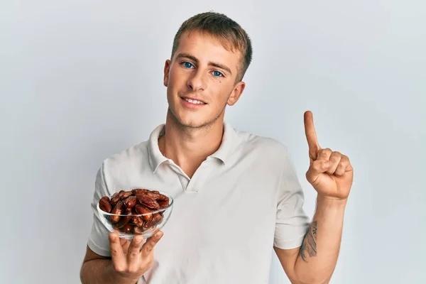 Young Caucasian Man Holding Bowl Dates Smiling Idea Question Pointing — Fotografia de Stock