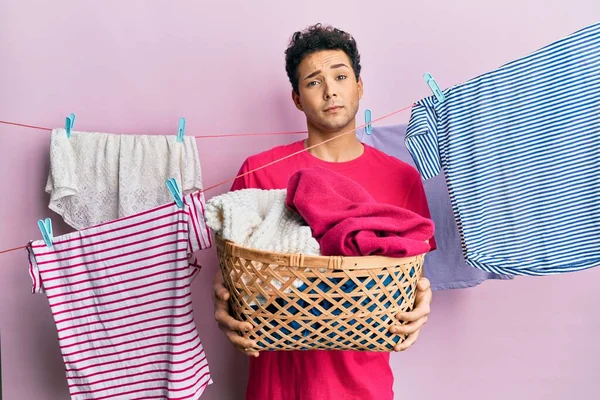 Handsome Hispanic Man Doing Laundry Holding Wicker Basket Shock Face — Fotografia de Stock