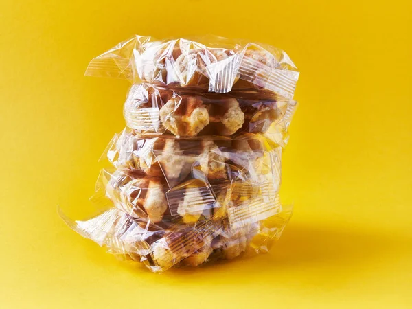 黄色の背景にビニール袋に包まれたおいしいワッフルの束 — ストック写真