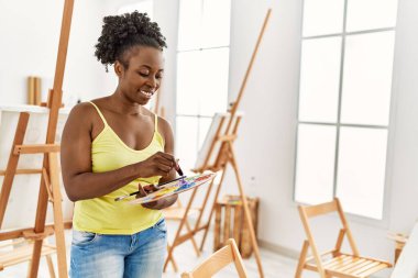 Genç Afrikalı Amerikalı sanatçı. Gülümsüyor. Sanat stüdyosunda mutlu çizimler..