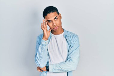 Genç Afro-Amerikalı adam günlük kıyafetler giyip kollarını kavuşturarak depresyondan sıkılmış ve yorgun görünüyor.. 