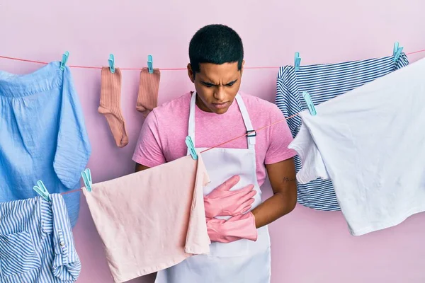 Joven Hombre Hispano Guapo Usando Delantal Más Limpio Sosteniendo Ropa — Foto de Stock