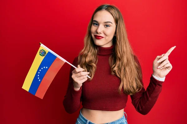 Młoda Blondynka Trzyma Wenezuelską Flagę Uśmiechając Się Szczęśliwa Wskazując Palcem — Zdjęcie stockowe