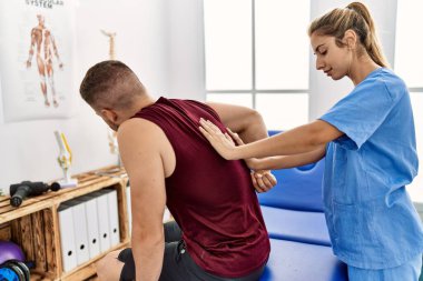 Genç İspanyol fizyoterapist kadın klinikteki İspanyol adama rehabilitasyon tedavisi uyguluyor..