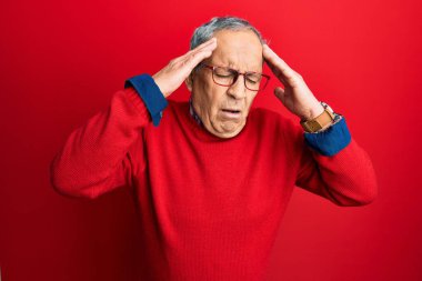 Handsome senior man with grey hair wearing casual clothes and glasses with hand on head for pain in head because stress. suffering migraine. 