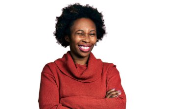 Afro saçlı, kollarını kavuşturmuş, kameraya seksi bir ifadeyle bakan, neşeli ve mutlu yüzlü Afro-Amerikalı bir kadın.. 