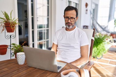 Middle age man using computer laptop at home depressed and worry for distress, crying angry and afraid. sad expression. 