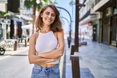 Sokakta kendinden emin gülümseyen beyaz bir kadın.