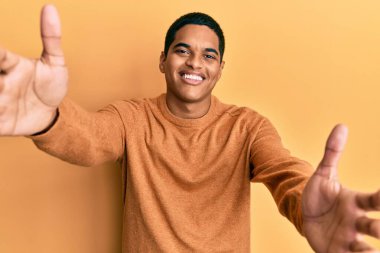 Sıradan bir kazak giyen genç, yakışıklı İspanyol adam kameraya sarılmak için gülümseyerek bakıyor. Mutluluğu kucaklayan neşeli bir ifade.. 