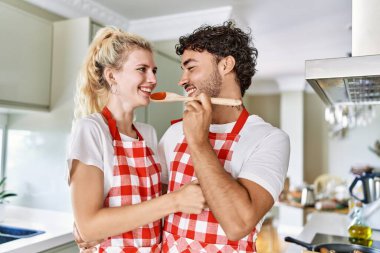 Genç çift gülümsüyor. Mutfakta lezzetli bir yemek..