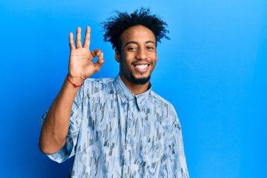 Young african american man with beard wearing casual clothes smiling positive doing ok sign with hand and fingers. successful expression. 