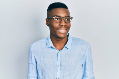 Afro-Amerikalı genç bir adam günlük kıyafetler ve gözlük takıyor. Taraf arıyor, profil pozu veriyor. Doğal bir yüzü ve kendine güvenen bir gülümsemesi var.. 
