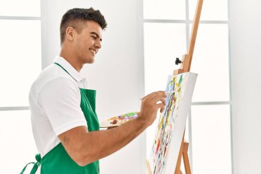 Genç İspanyol adam resim stüdyosunda kendine güvenen gülümsüyor.