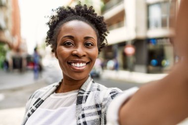Gülümseyen Afrikalı Amerikalı genç kız şehirdeki akıllı telefondan selfie çekiyor..