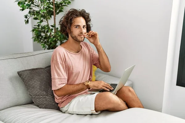 Young Hispanic Man Sitting Sofa Home Using Laptop Mouth Lips —  Fotos de Stock